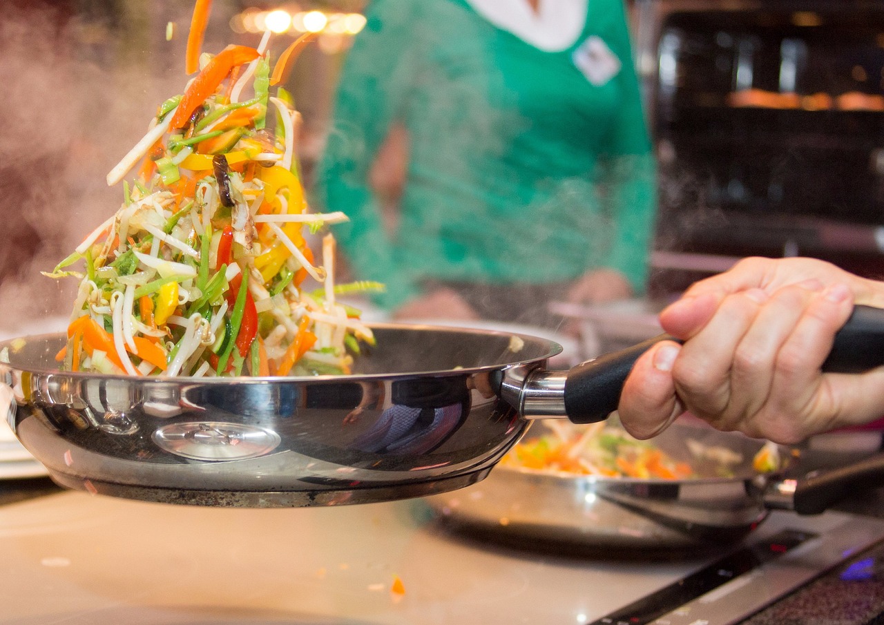Chef avec qui fait sauter des légumes dans une poêle